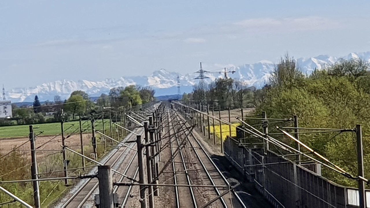 elektrifizierte Bahnstrecke, im Hintergrund die Alpen